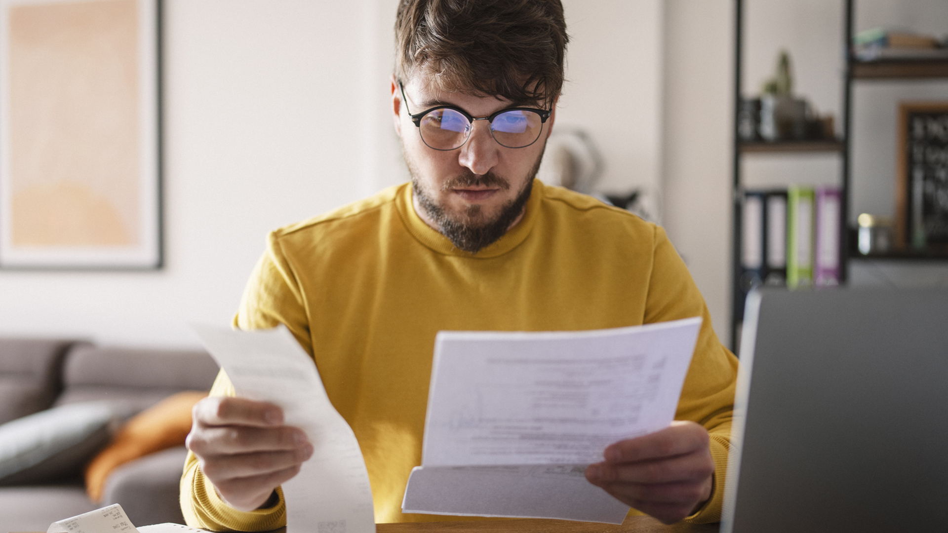 A young man on his computer reviewing bills and receipts