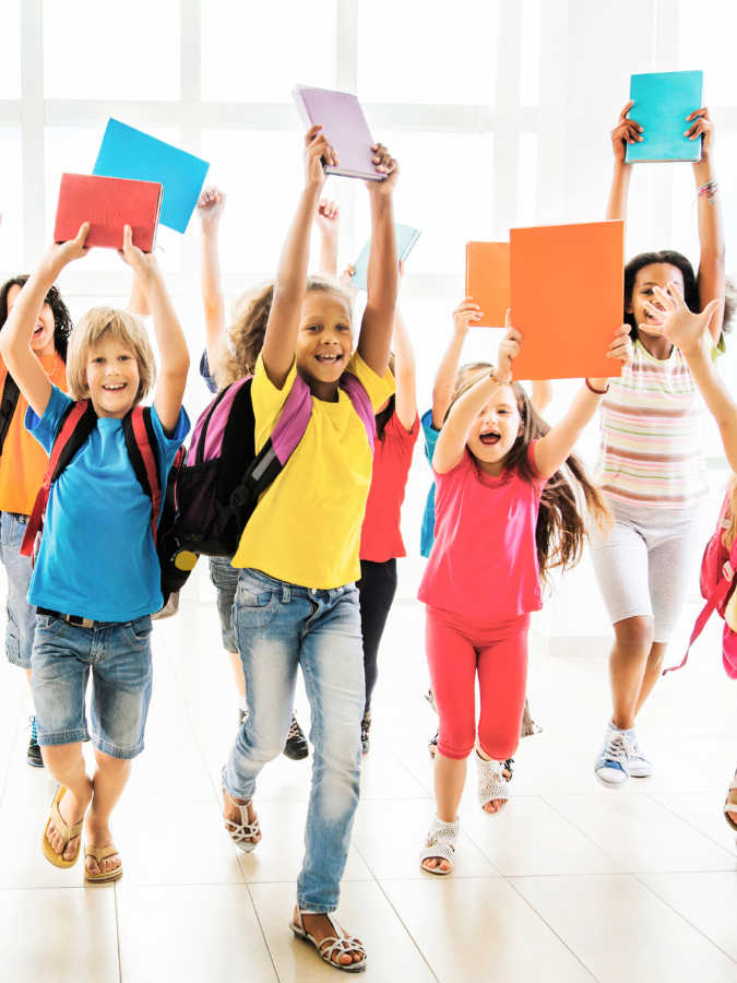 kids back to school smiling and running with book in hand 