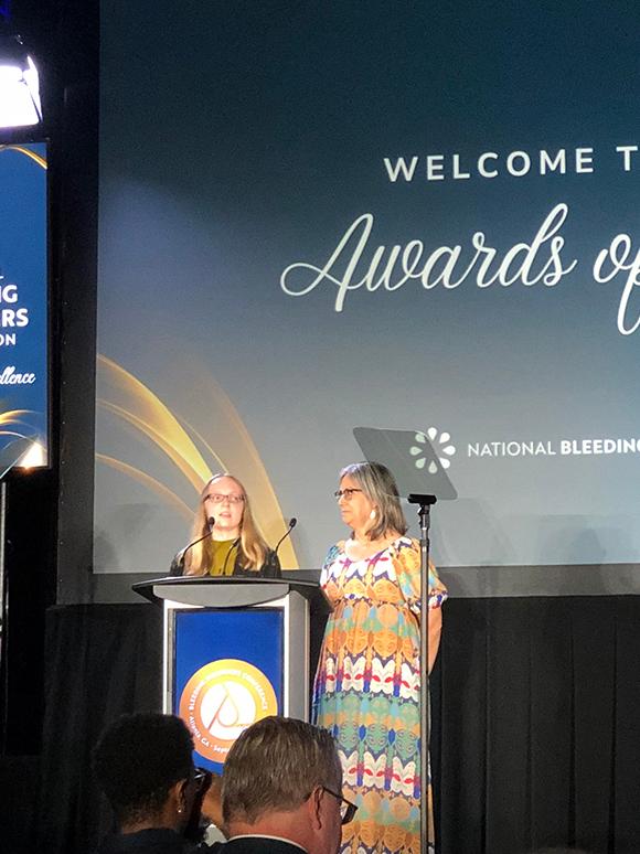 Two women speaking at the podium for the 2024 Awards of Excellence at BDC