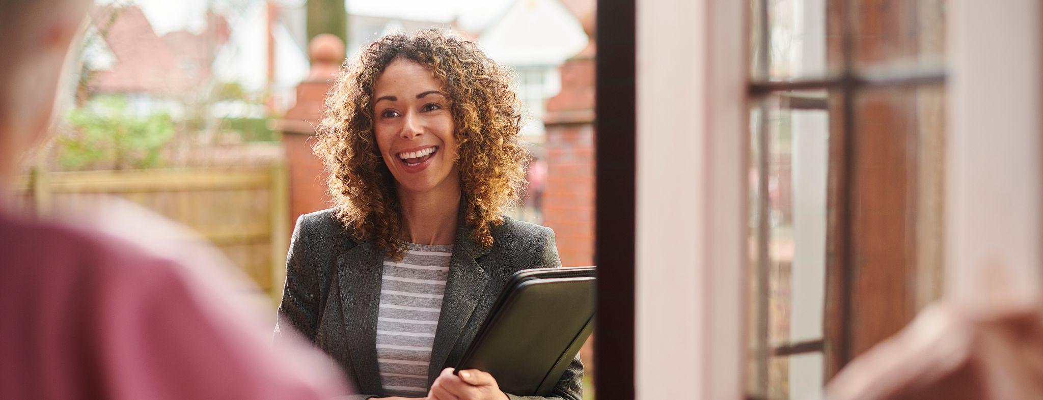 Social Worker smiling at the front door of a house