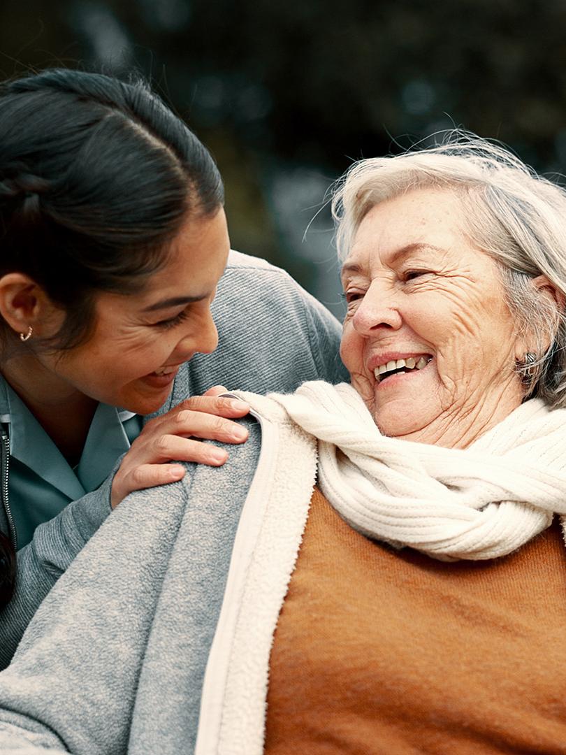 Elderly woman smiling at young woman caretaker