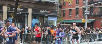 A side view of marathon runners and a crowd watching