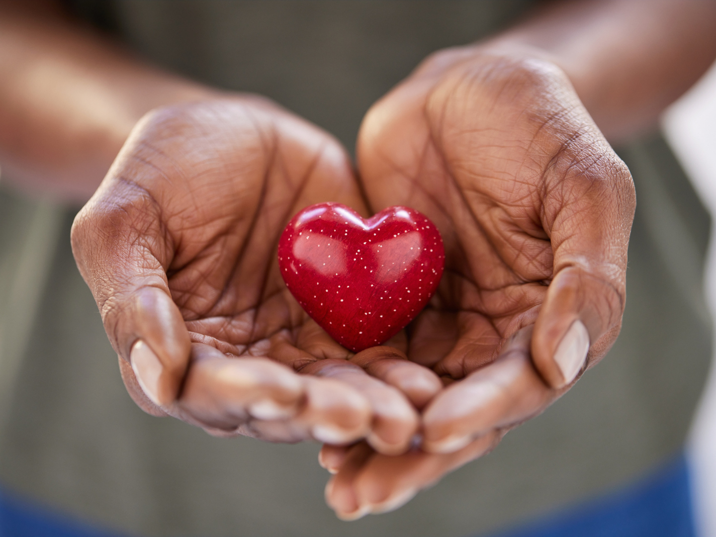 A person holding a small red heart in their hands