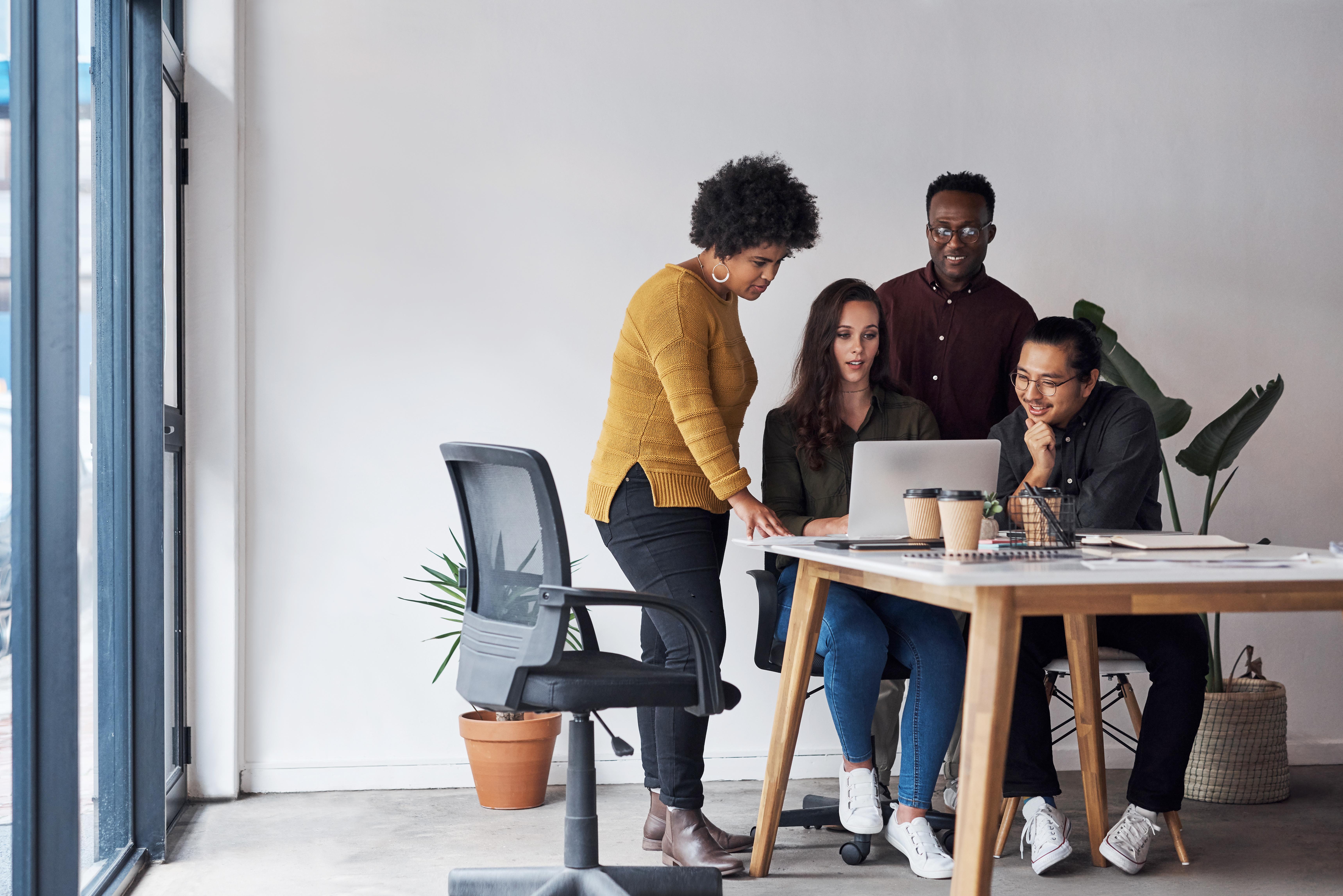 A group of people working together at a table with a laptop computer on it.