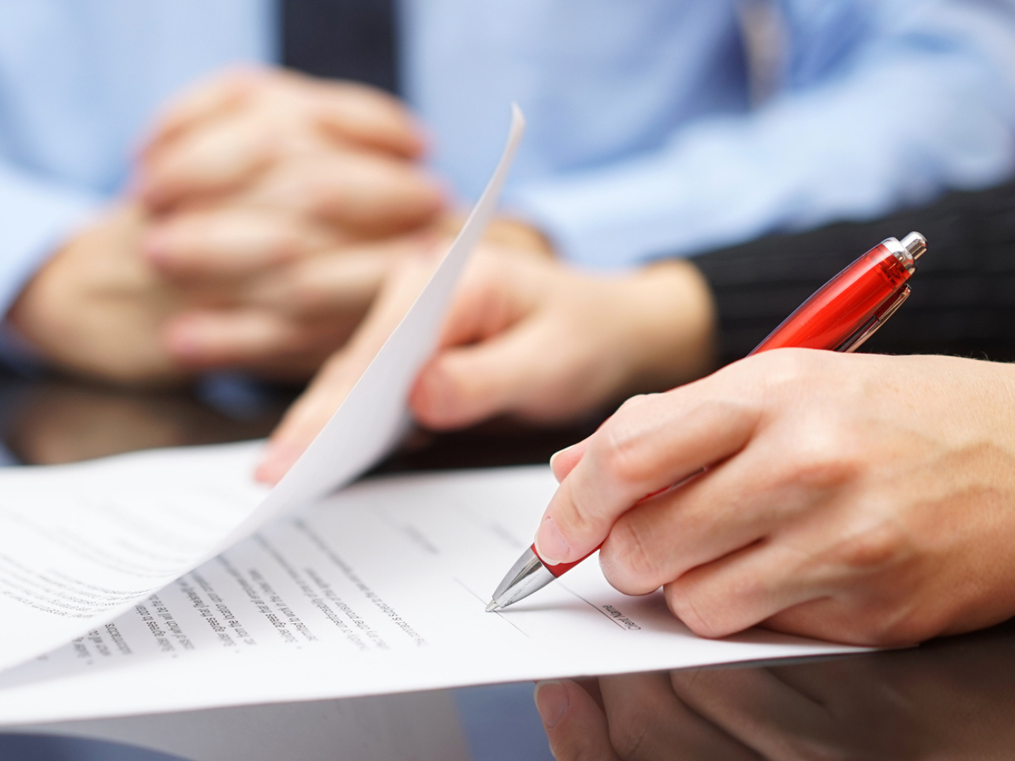 A person signing a legal document next to another person